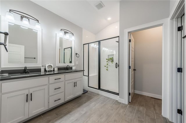 full bath featuring wood finish floors, a sink, a shower stall, and double vanity