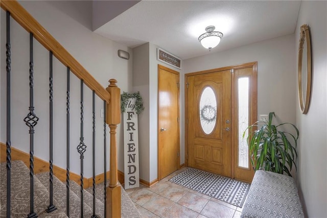 foyer entrance with light tile patterned floors and stairs