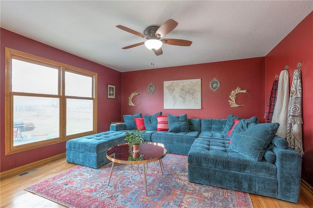 living area with ceiling fan, a textured ceiling, wood finished floors, and visible vents