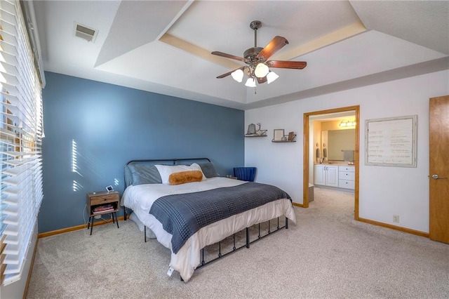 carpeted bedroom featuring baseboards, visible vents, a raised ceiling, and a ceiling fan