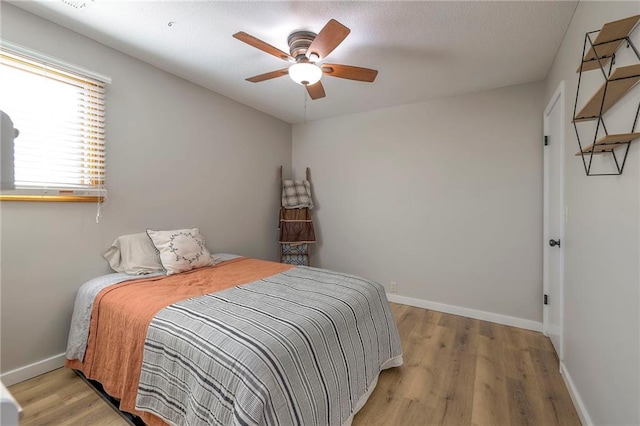 bedroom featuring light wood-style floors, baseboards, and a ceiling fan