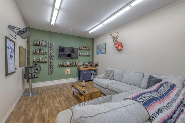 living area with a dry bar, baseboards, and wood finished floors