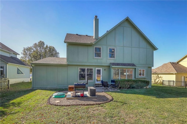 back of property featuring a shingled roof, a chimney, fence, a yard, and a patio area