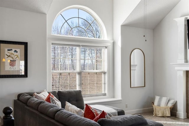 carpeted living area featuring lofted ceiling, a fireplace, a textured ceiling, and baseboards