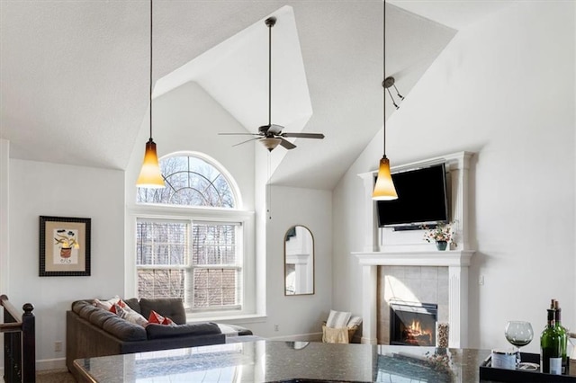 living area featuring a fireplace, high vaulted ceiling, and a ceiling fan