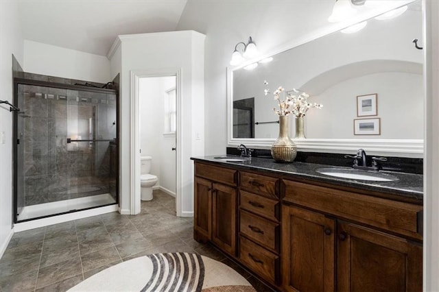 full bathroom with a sink, a shower stall, toilet, and double vanity