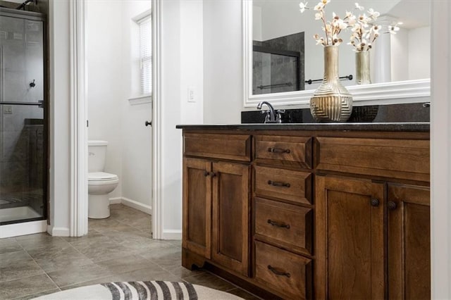 bathroom featuring toilet, an inviting chandelier, vanity, a shower stall, and baseboards