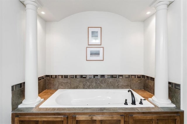 bathroom featuring a garden tub and decorative columns