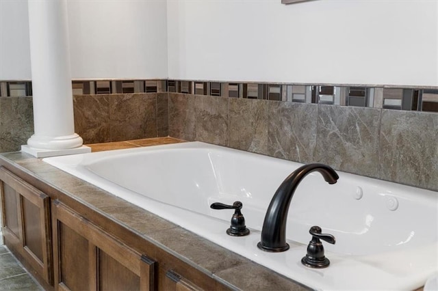 bathroom with a garden tub and ornate columns