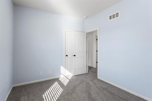 unfurnished room featuring carpet, visible vents, and baseboards