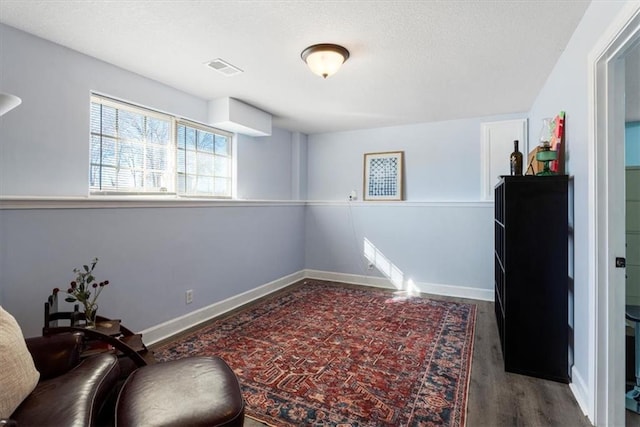 living area with visible vents, baseboards, and wood finished floors