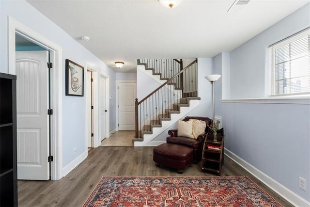 foyer entrance with stairway, wood finished floors, and baseboards