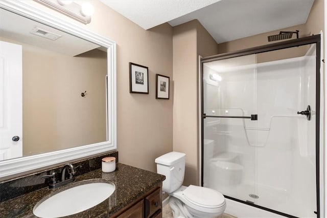 full bathroom featuring toilet, a stall shower, visible vents, and vanity