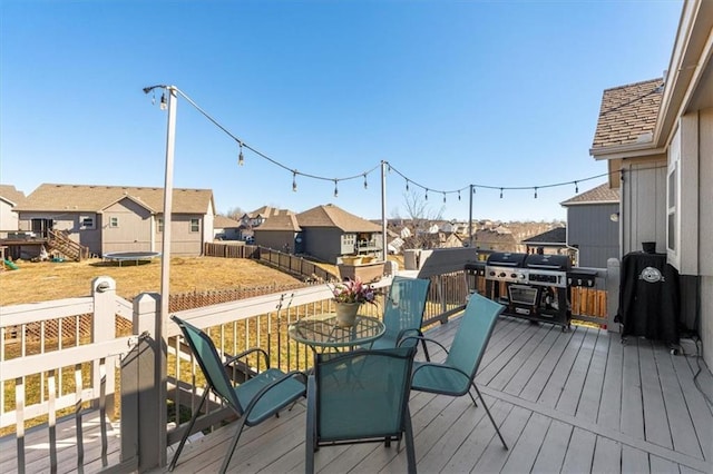 wooden terrace with a trampoline, fence, and a residential view