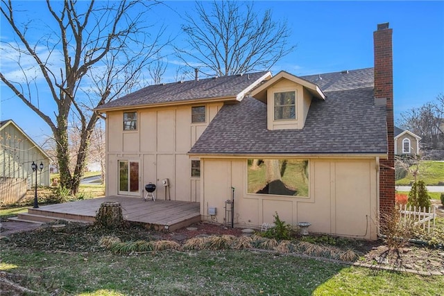 back of property with board and batten siding, a shingled roof, a lawn, a chimney, and a deck