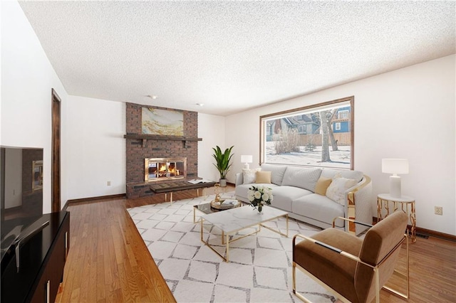 living area with baseboards, a textured ceiling, and wood finished floors