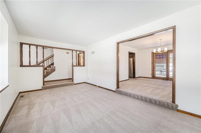 empty room with stairway, baseboards, a notable chandelier, and carpet flooring