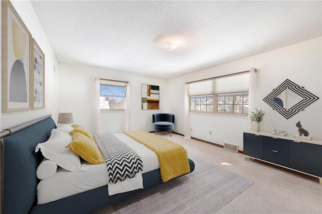 carpeted bedroom featuring baseboards, visible vents, and a textured ceiling