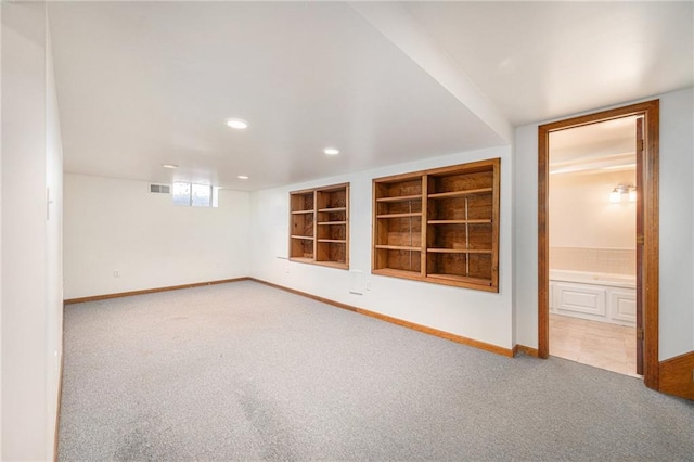 spare room featuring carpet flooring, baseboards, visible vents, and built in shelves