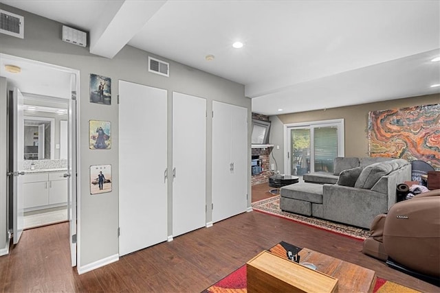 living area featuring a glass covered fireplace, wood finished floors, and visible vents