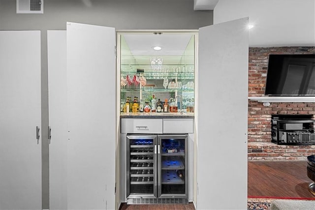 bar featuring a bar, wine cooler, wood finished floors, and visible vents