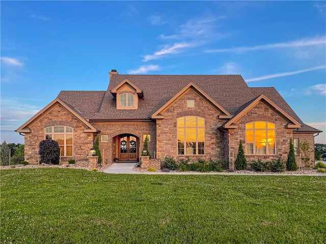 french country style house featuring roof with shingles, a front yard, a chimney, and french doors