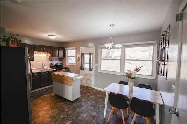 kitchen with light countertops, backsplash, appliances with stainless steel finishes, a sink, and a kitchen island