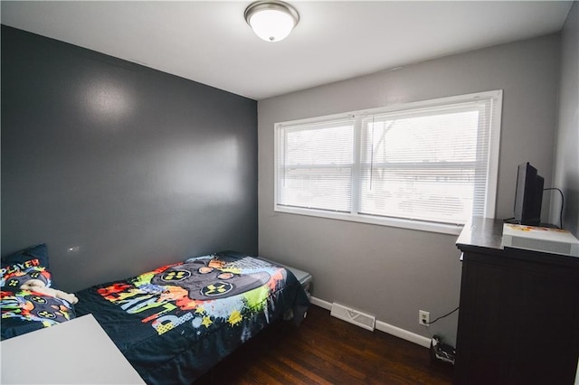 bedroom with wood finished floors, visible vents, and baseboards