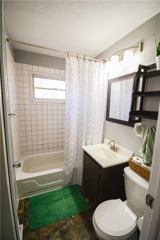 bathroom with shower / tub combo with curtain, a textured ceiling, toilet, and vanity