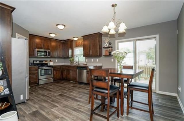 kitchen featuring stainless steel appliances, a healthy amount of sunlight, baseboards, and wood finished floors