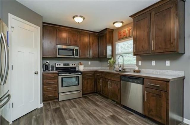 kitchen with dark brown cabinetry, dark wood-style floors, appliances with stainless steel finishes, and light countertops