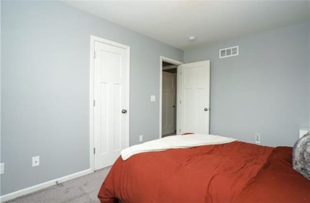 bedroom featuring light carpet, visible vents, and baseboards