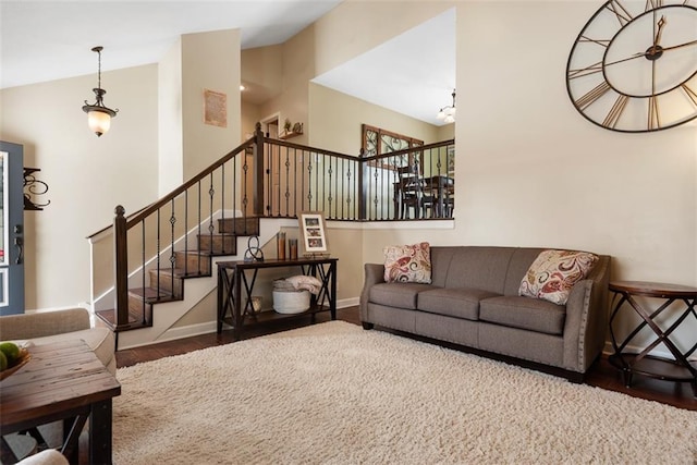 living room featuring lofted ceiling, stairway, wood finished floors, and baseboards