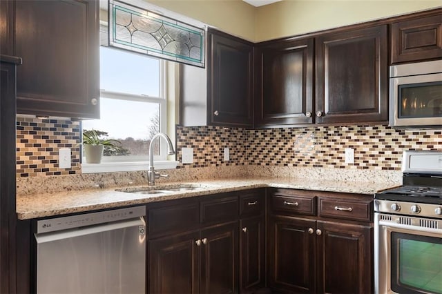 kitchen featuring tasteful backsplash, dark brown cabinets, light stone countertops, appliances with stainless steel finishes, and a sink