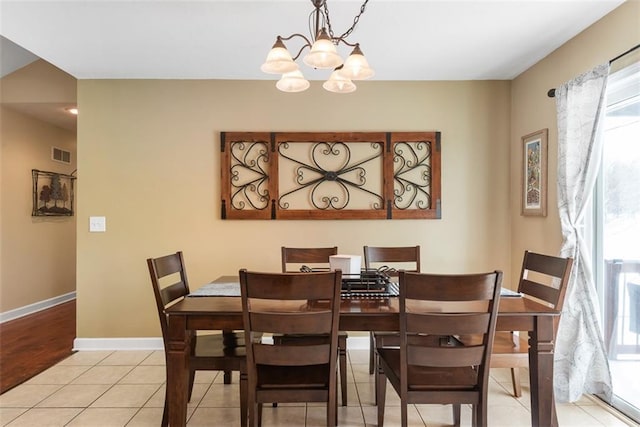 dining room with light tile patterned floors, baseboards, visible vents, and a chandelier