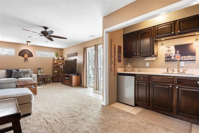 kitchen featuring ceiling fan, dark brown cabinetry, open floor plan, light colored carpet, and light countertops