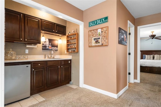 kitchen with dark brown cabinetry, light countertops, light carpet, fridge, and a sink