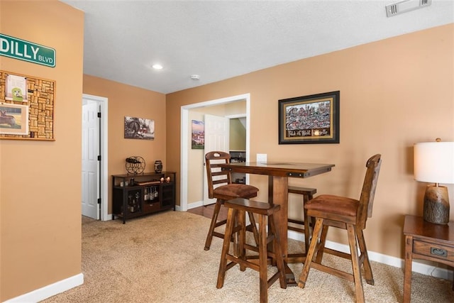 dining area with visible vents, light colored carpet, and baseboards