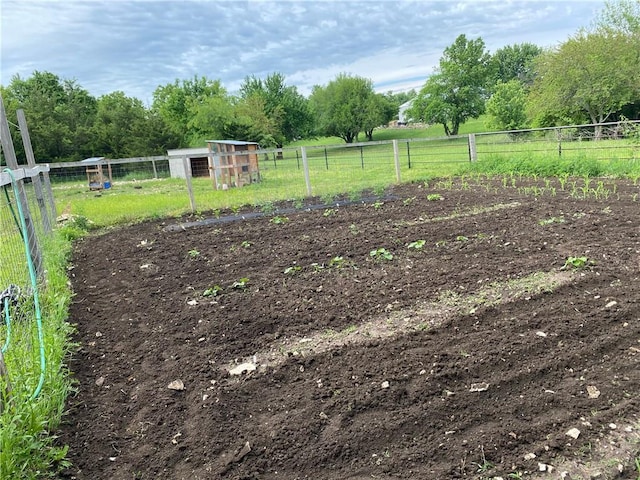 view of yard featuring an outdoor structure, a rural view, fence, and exterior structure