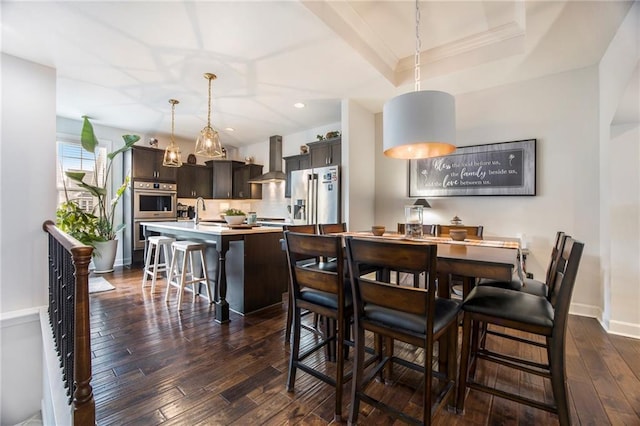 dining area featuring dark wood-type flooring, a tray ceiling, baseboards, and recessed lighting