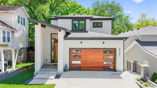 view of front of home featuring brick siding, stucco siding, a shingled roof, concrete driveway, and an attached garage