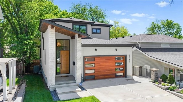 4731 Fairmount Ave, Kansas City, MO 64112 - modern home featuring fence, an attached garage, concrete driveway, stucco siding, and cooling unit