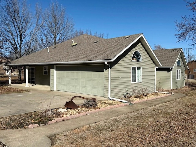 view of side of home featuring a shingled roof, driveway, and an attached garage