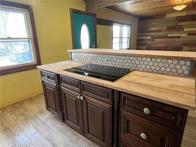 kitchen with light wood finished floors, wood ceiling, black electric stovetop, dark brown cabinets, and wooden counters