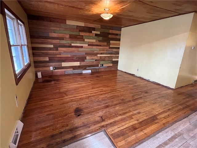 unfurnished living room with wood finished floors, visible vents, and wooden walls