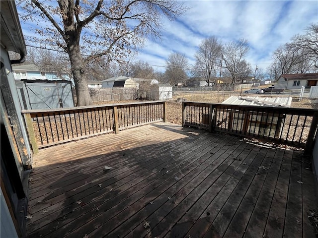 deck with a fenced backyard, an outdoor structure, and a storage shed