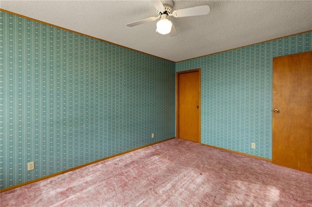 spare room featuring ceiling fan, a textured ceiling, wallpapered walls, and carpet