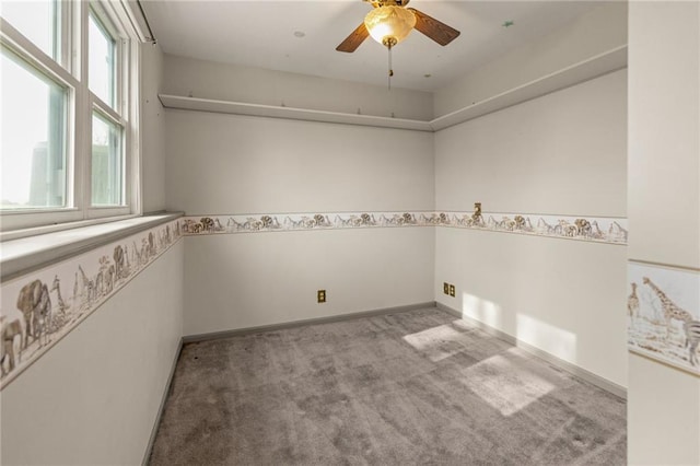 carpeted empty room with a ceiling fan and baseboards