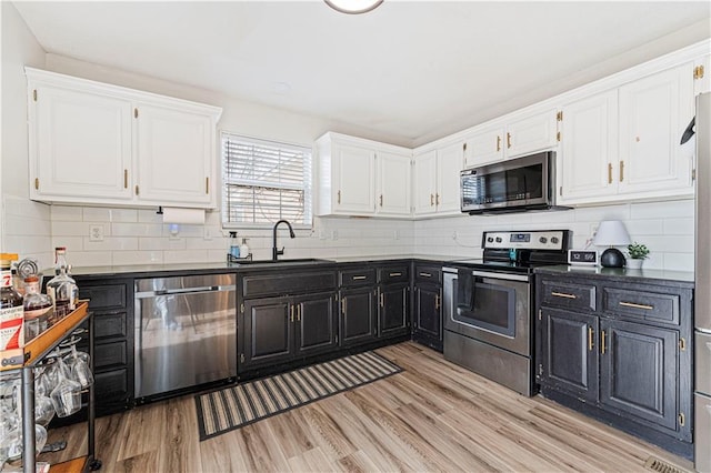 kitchen featuring stainless steel appliances, dark countertops, a sink, and dark cabinets