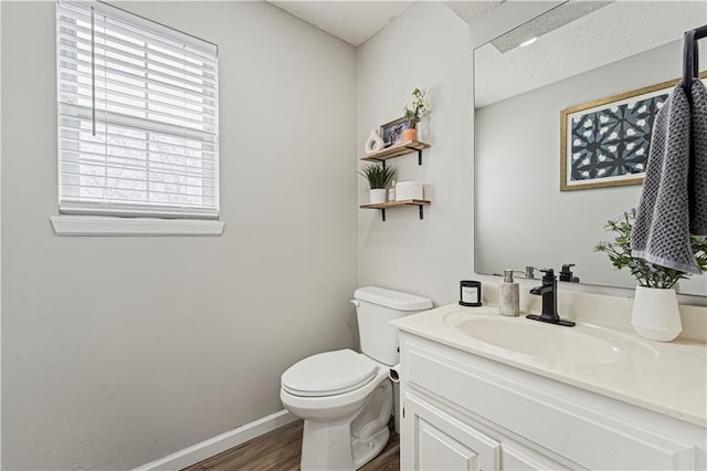 half bathroom with toilet, baseboards, wood finished floors, and vanity